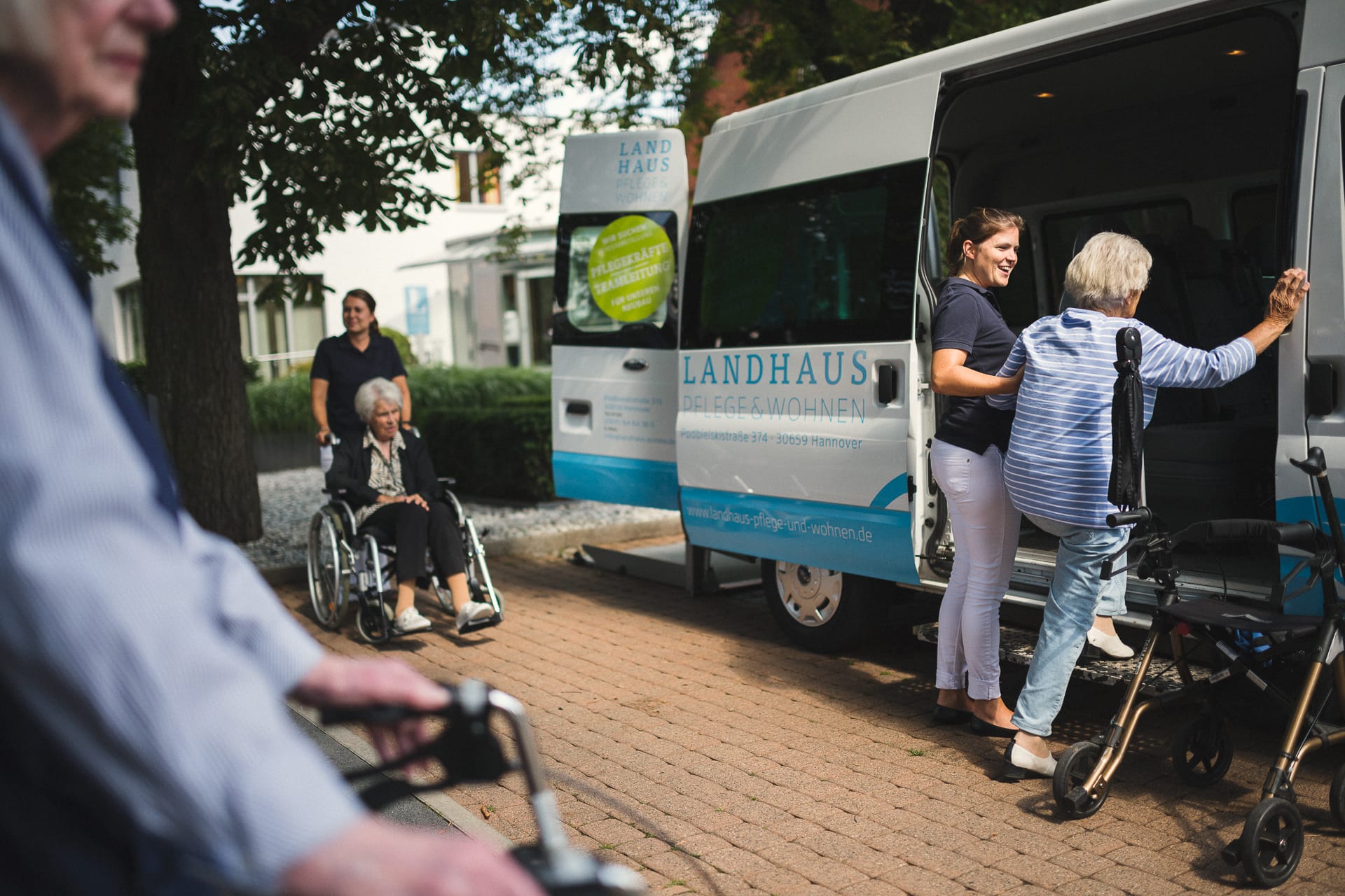 Pfleger helfen Frauen und Männern mit Rollator und Rollstuhl ins Auto Ausflug beim Pflegeheim