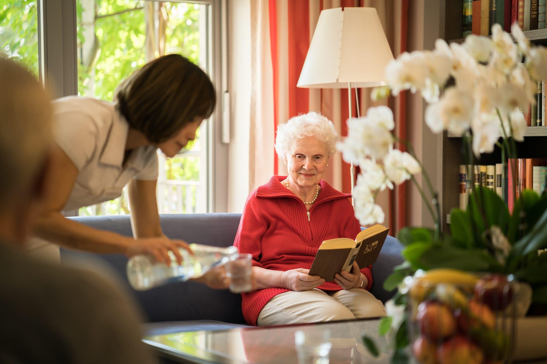 Oma bekommt Getränke bei Lesegruppe Gruppenangebot Betreuung Pflegeheim in Hannover Landhaus Pflege und Wohnen