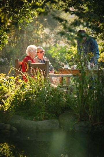 Zwei Bewohner sitzen am Tisch im Garten des Landhaus Pflege und Wohnen, Altenheim Hannover