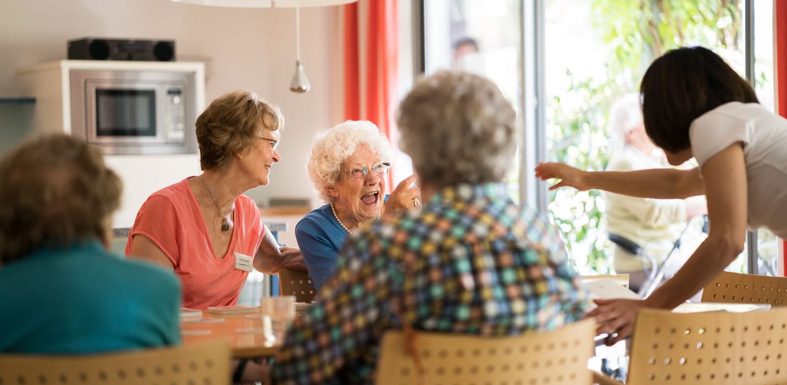 Bewohner spielen Gesellschaftsspiel mit Pflegern, lachen, Betreuung Altenheim in Hannover Landhaus Pflege und Wohnen