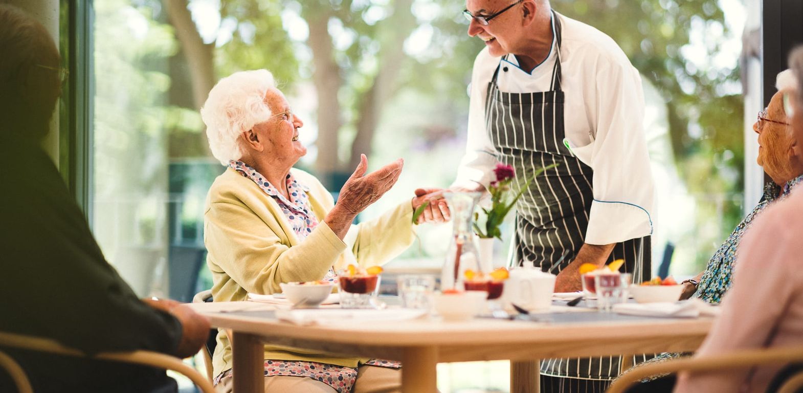 Koch und ältere Frau unterhalten sich im Restaurant im Pflegeheim in Hannover Landhaus Pflege und Wohnen