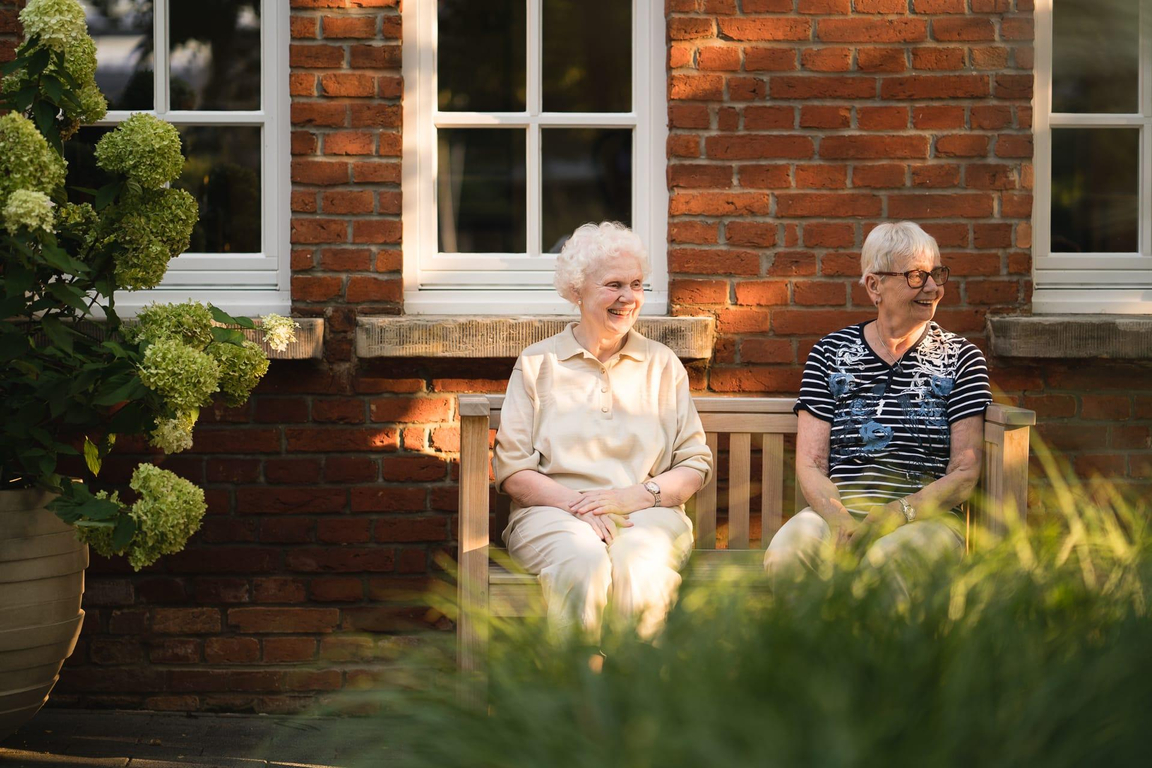 Zwei Bewohnerinnen sitzen draußen auf einer Bank beim Landhaus Pflege und Wohnen Hannover